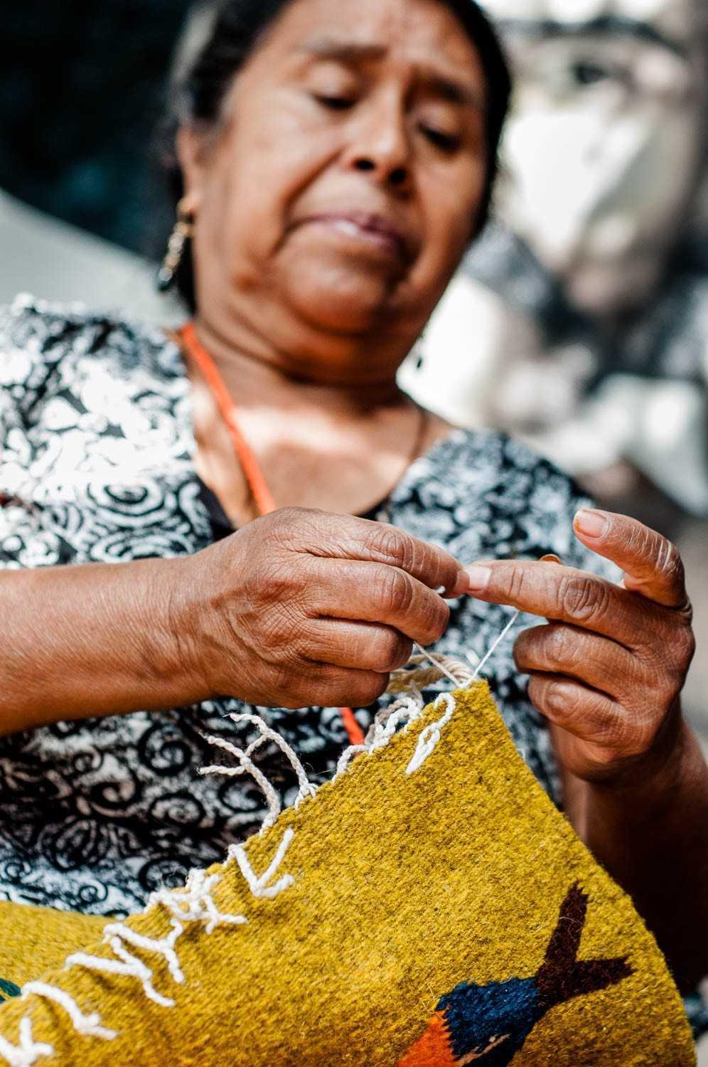 Antonieta finishes the ends of a carpet.