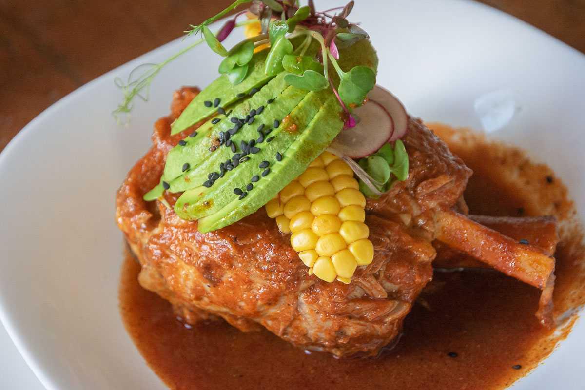 Chamorro (marinated pork shank) with avocado and a slice of corn.