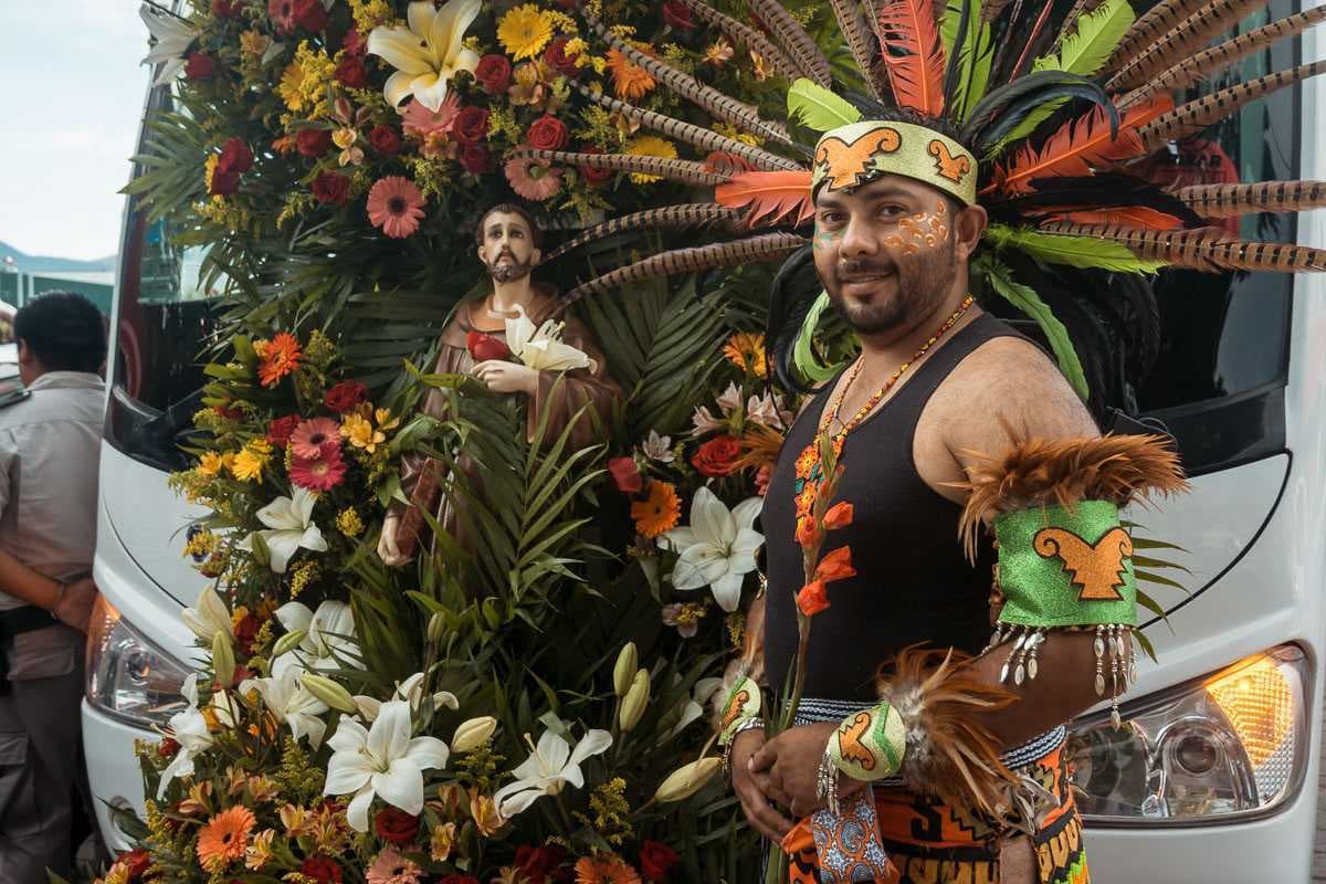 Aztec dancer Humberto Ayala stands in front of a bus in 2018 on the day when the bus drivers sponsored the fiestas.